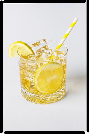 Ein Getränkeglas gefüllt mit Eistee von nosuga. Im Glas sind Eiswürfel, Zitronenscheiben und ein Strohhalm.