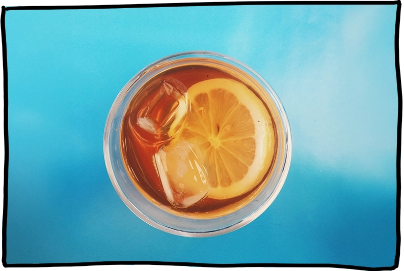 Eisteegetränk im Glas mit Eiswürfel und Zitronenscheibe