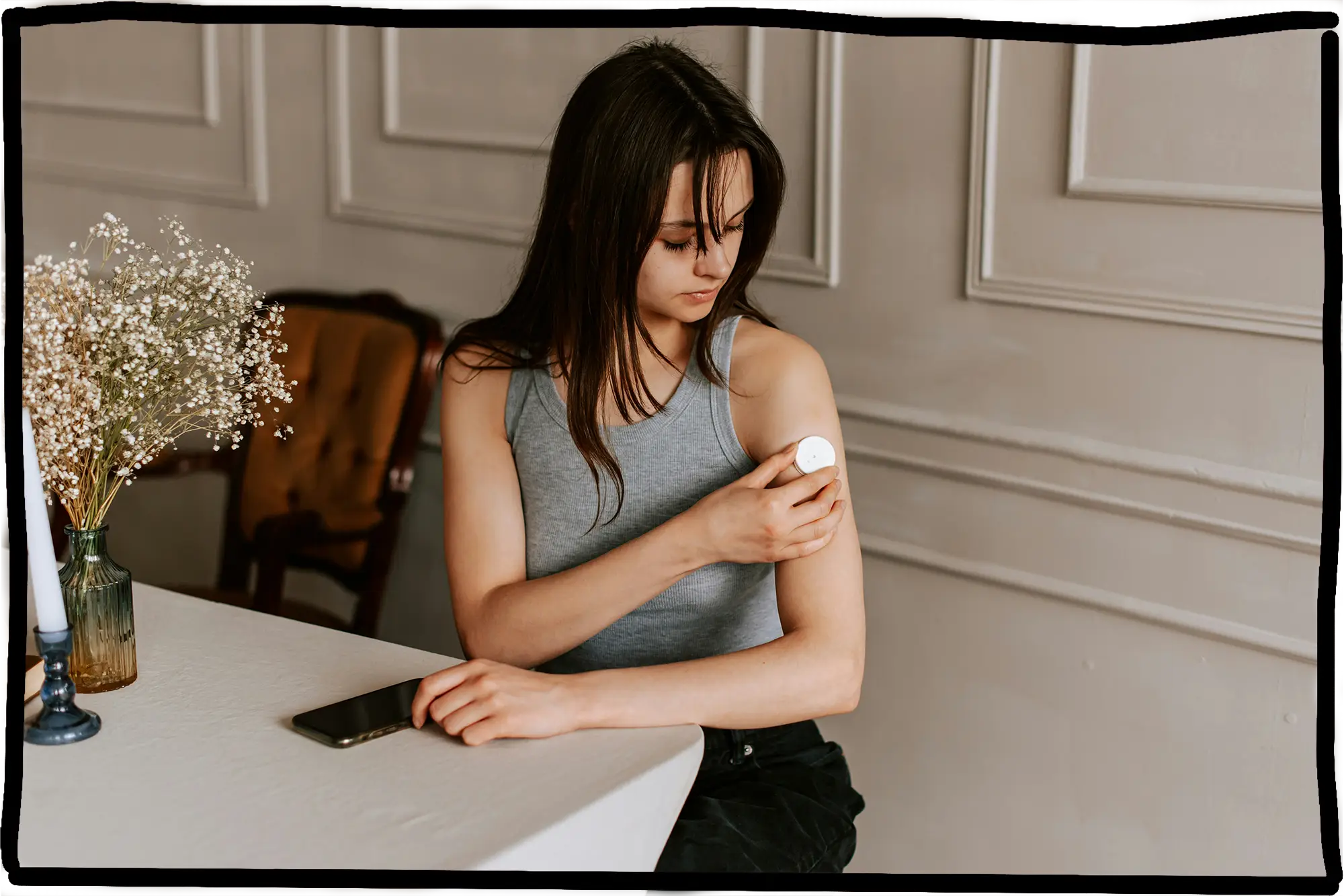 Eine Junge Dame, die ein Diabetes Gerät an ihren Oberarm befestigt. 