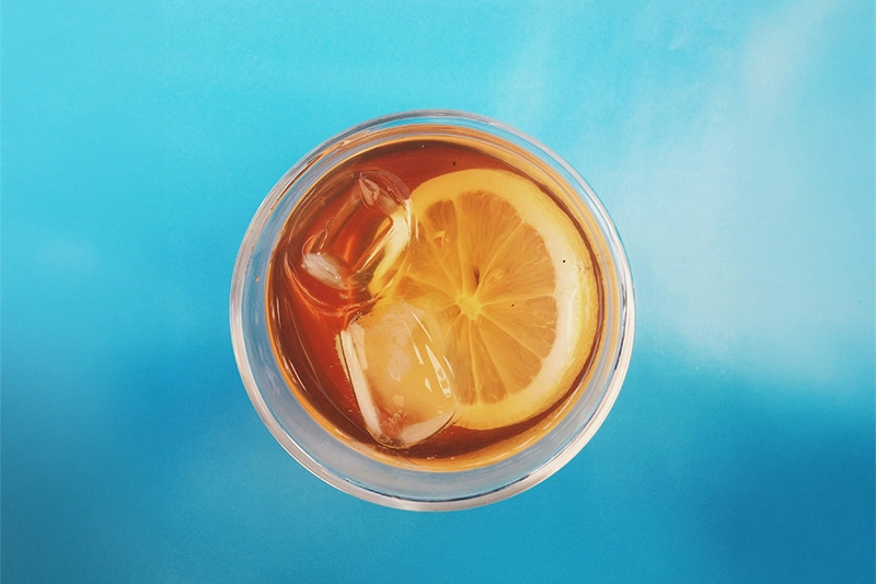 Eisteegetränk im Glas mit Eiswürfel und Zitronenscheibe