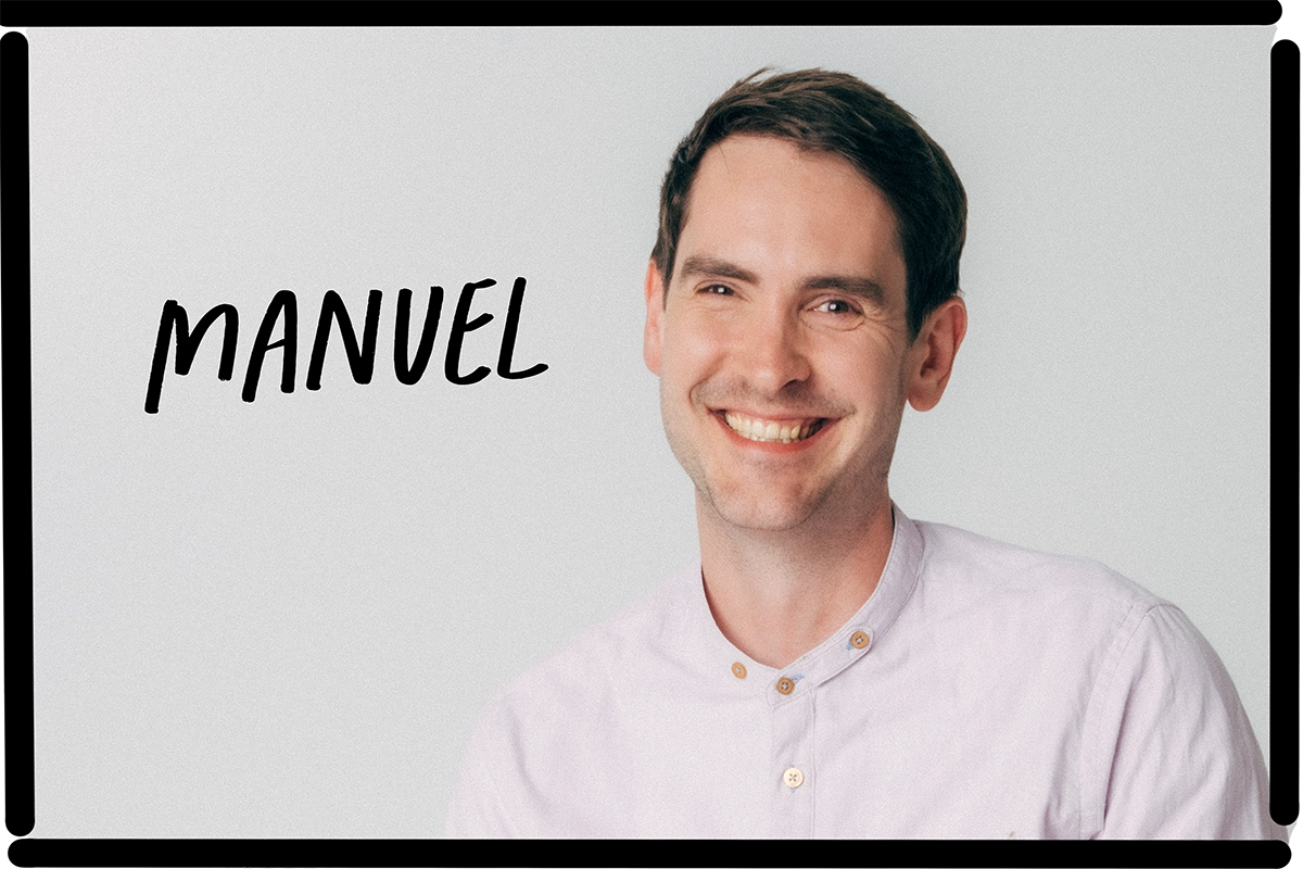 Ein Mitarbeiter von nosuga sitz auf einem Stuhl vor weißem Hintergrund und lacht in die Kamera. Sein Name steht auf dem Bild: Manuel.